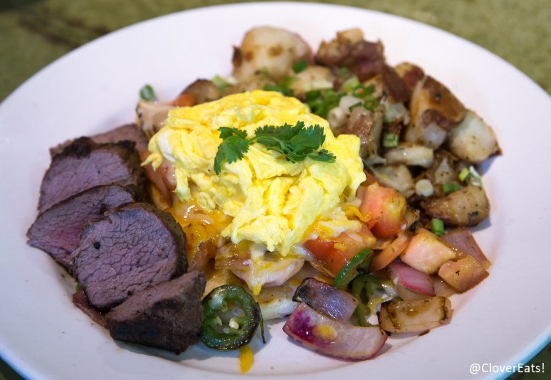 Arepa: petit tenderloin over a corn arepa topped with scrambled eggs, cheese, red onions, tomato, cilantro, lime, jalapeno, potatoes